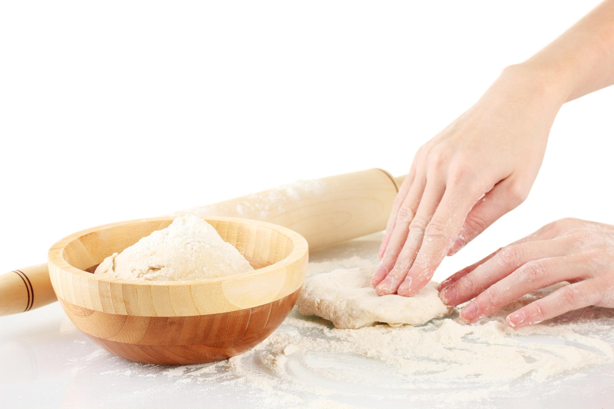 Close-up of hands kneading dough on a light surface